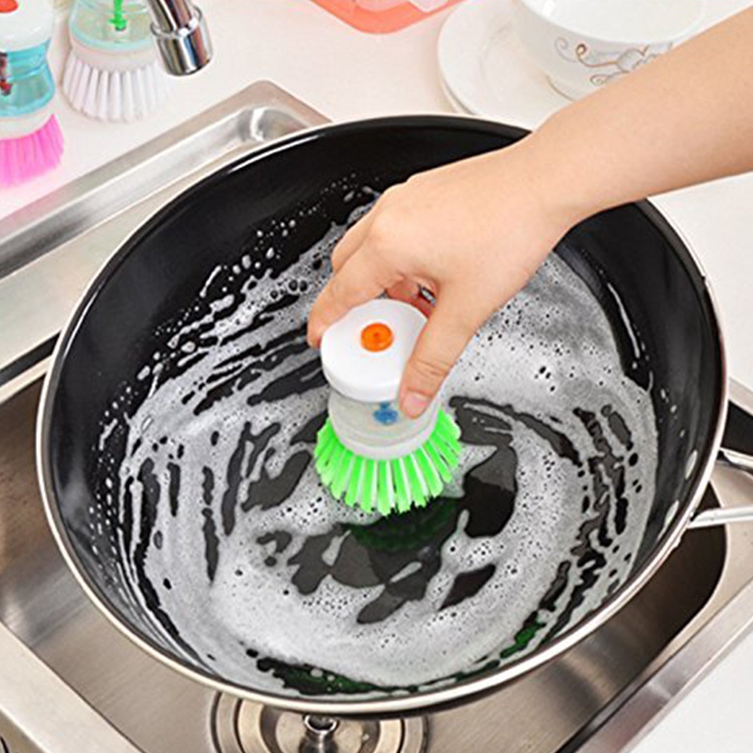 Wukusy cleaning brush with soap dispenser scrubbing a black frying pan in the kitchen sink