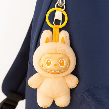 Cute cartoon keychain with hook in yellow holding a soft plush bunny attached to navy blue backpack