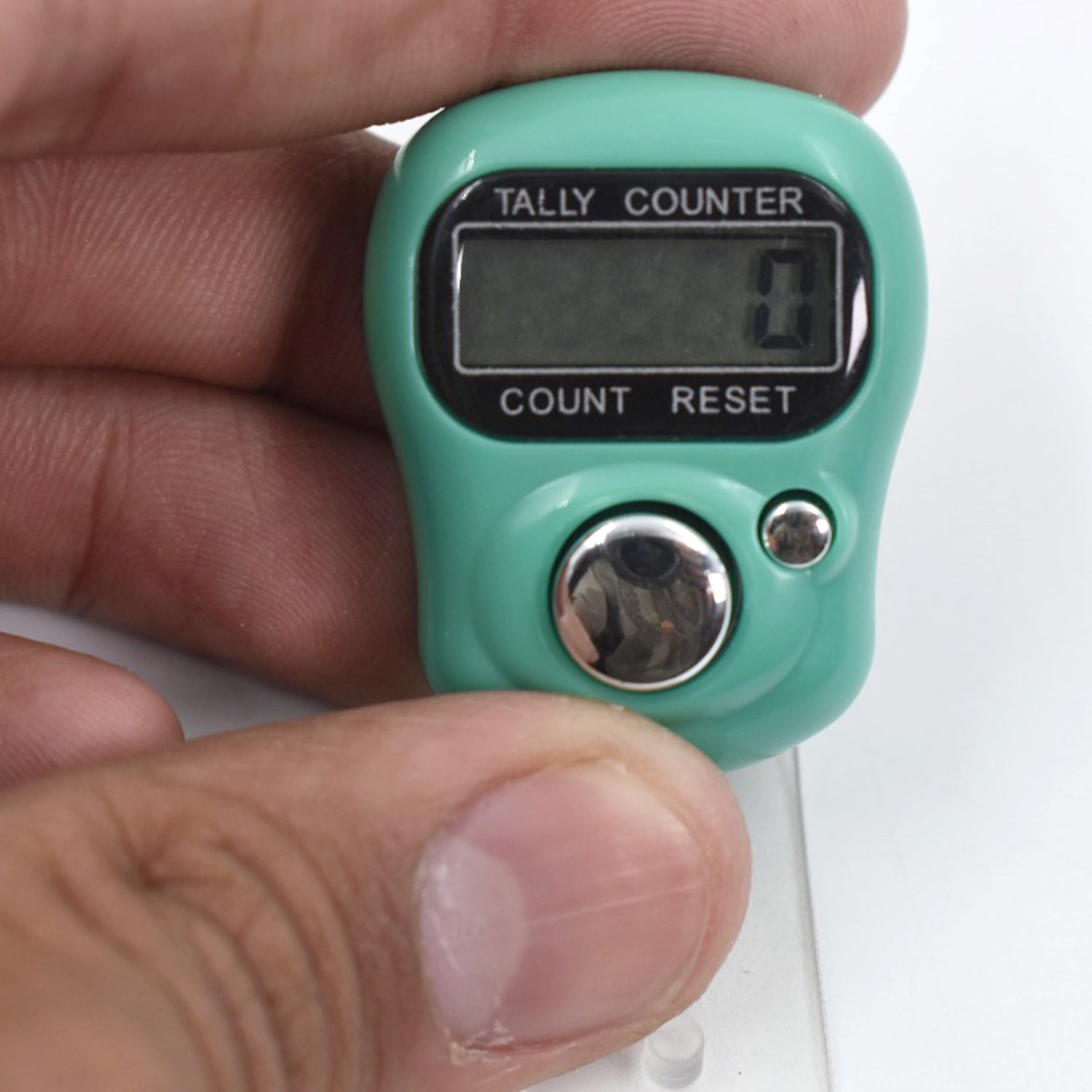 Wukusy digital finger tally counter in teal held between fingers with clear LCD display and metal buttons