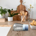 Wukusy glass salt bottle set on kitchen countertop with wooden utensils and plants in background