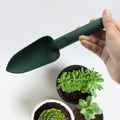 Wukusy heavy duty garden hand trowel in green held above potted succulent plants