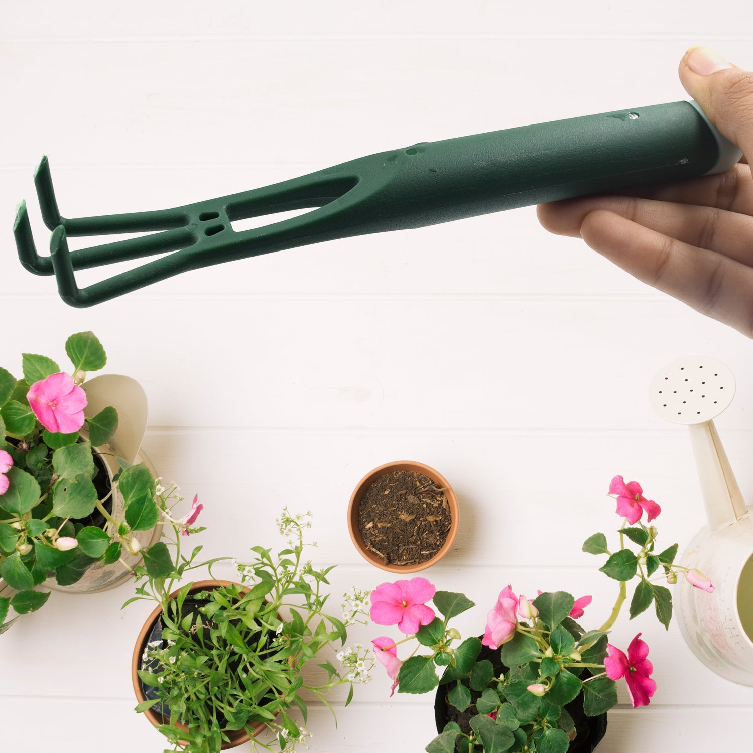 Wukusy heavy duty garden hand trowel with green handle held above potted flowering plants and soil