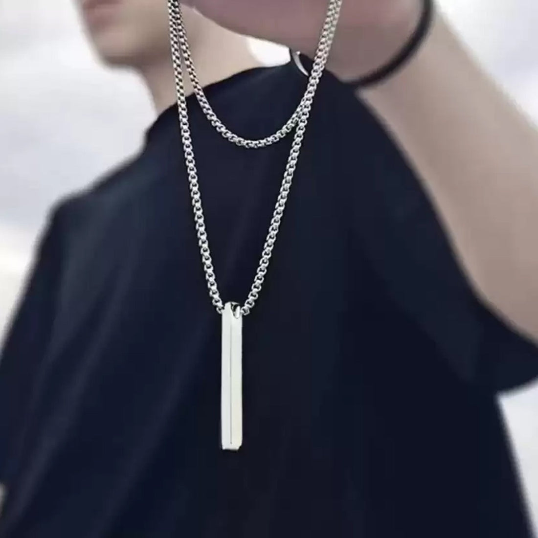 Wukusy minimalist bar pendant necklace in silver with a sleek rectangular pendant and ball chain on blue background