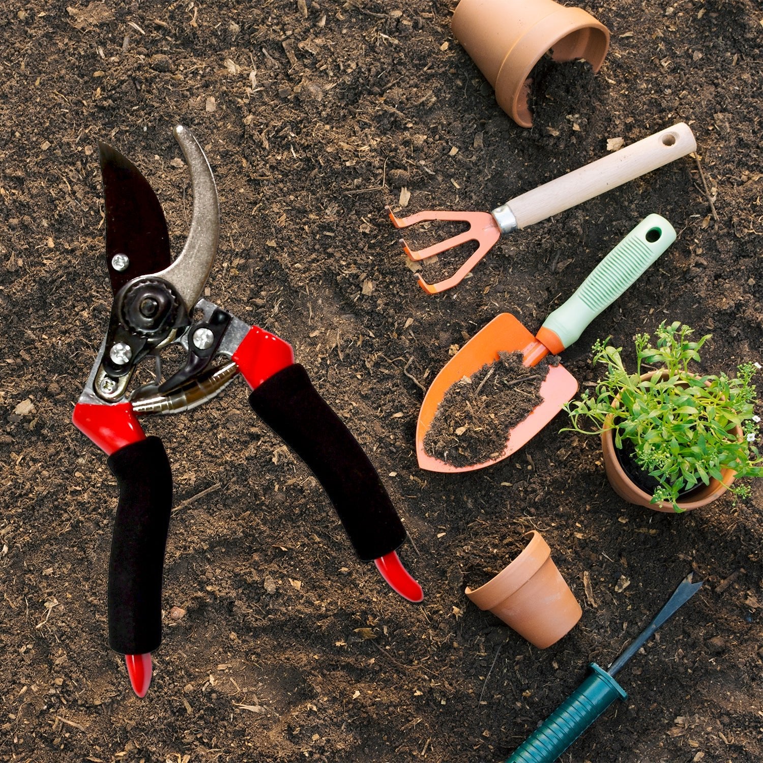 Wukusy sharp garden cutter for flowers with red and black handles placed on soil next to gardening tools and pots