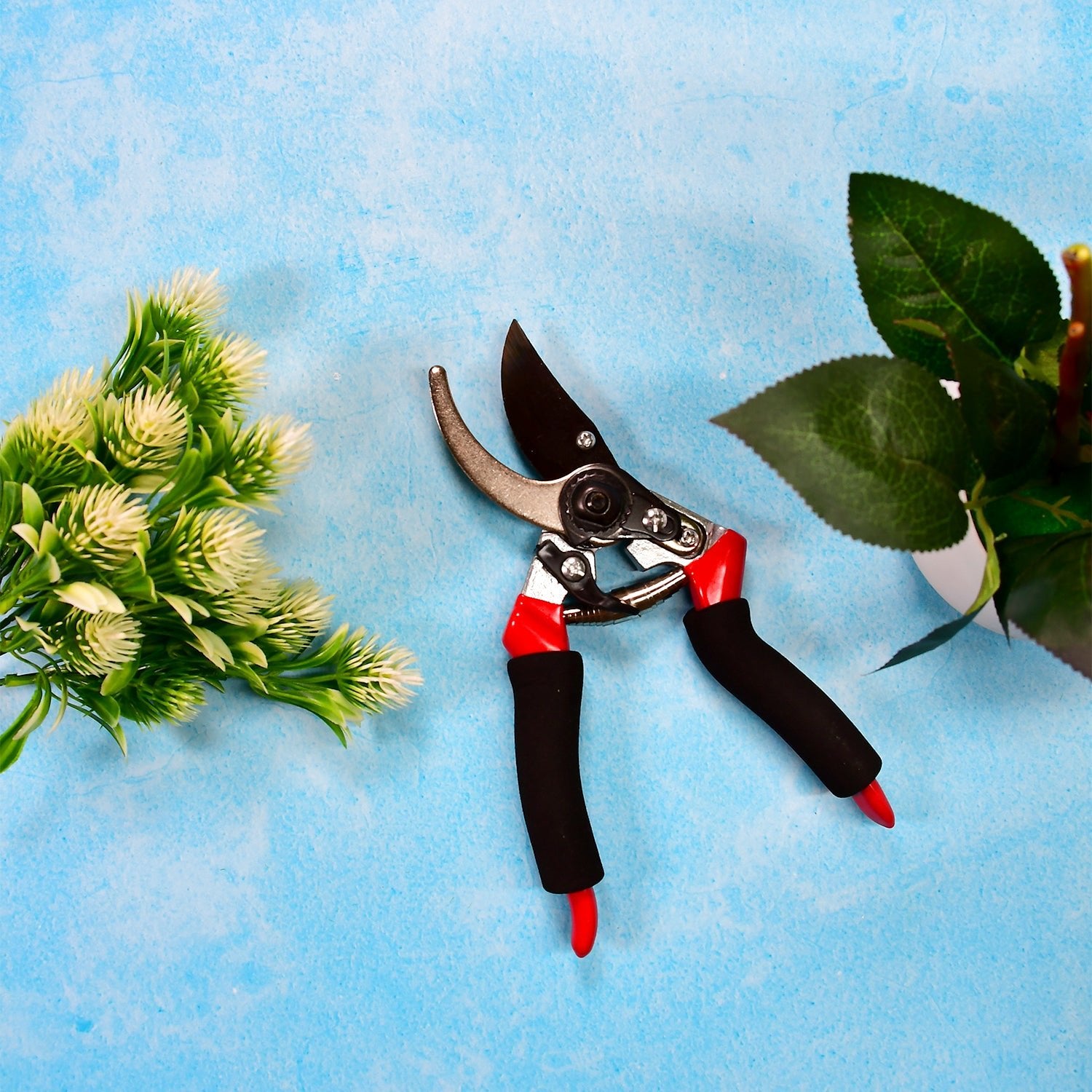 Sharp garden cutter for flowers with ergonomic black and red handles on blue background