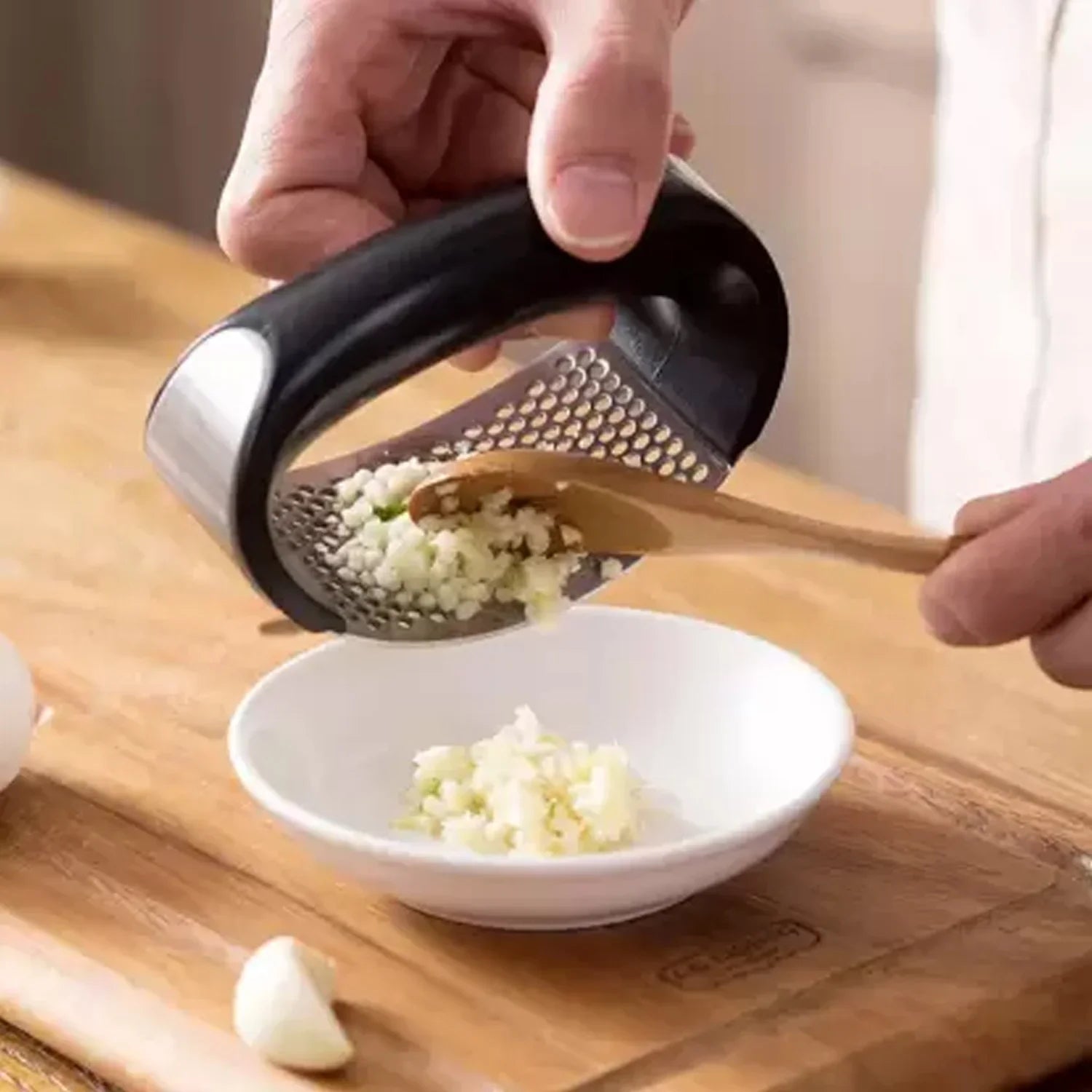 Stainless Steel Garlic Crusher with Ergonomic Handle - Market FindsMarket Findsstainless steel garlic crusher with black handle crushing garlic into a white bowl