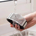 Stainless Steel Garlic Crusher with Ergonomic Handle - Market FindsMarket Findsstainless steel garlic crusher being rinsed under running water in a kitchen sink